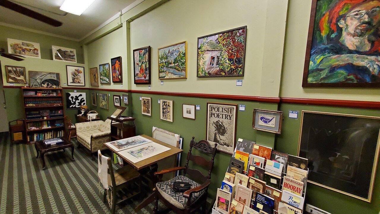 An image of a room with a green wall, showing paintings on the wall.