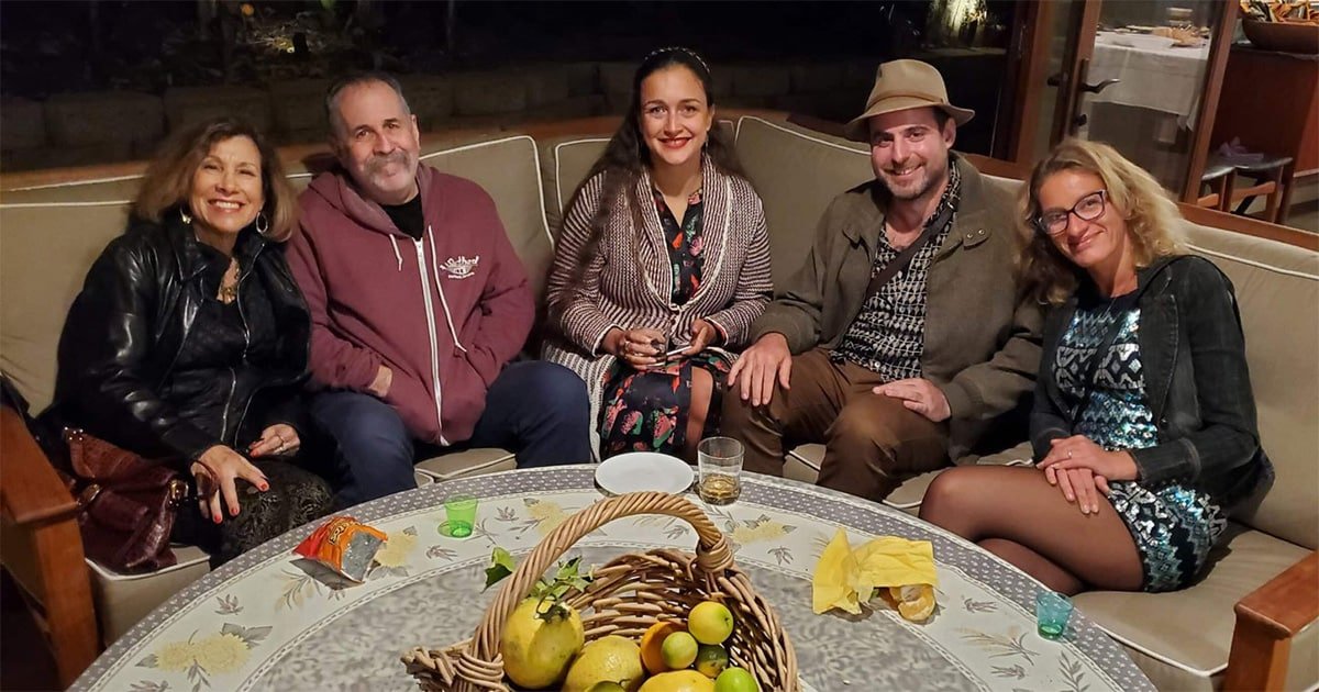 a group of people sitting on a couch and smiling at the camera