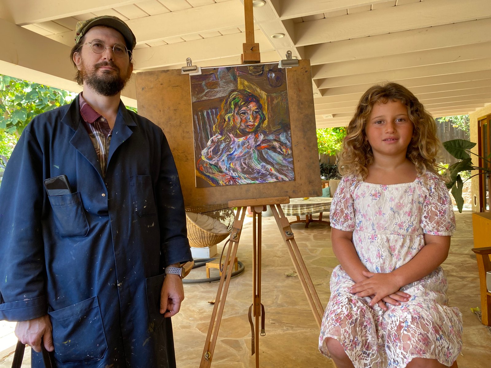 A man and a girl posing in front of a portrait of the girl