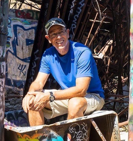 Person sitting with metal railing behind him.