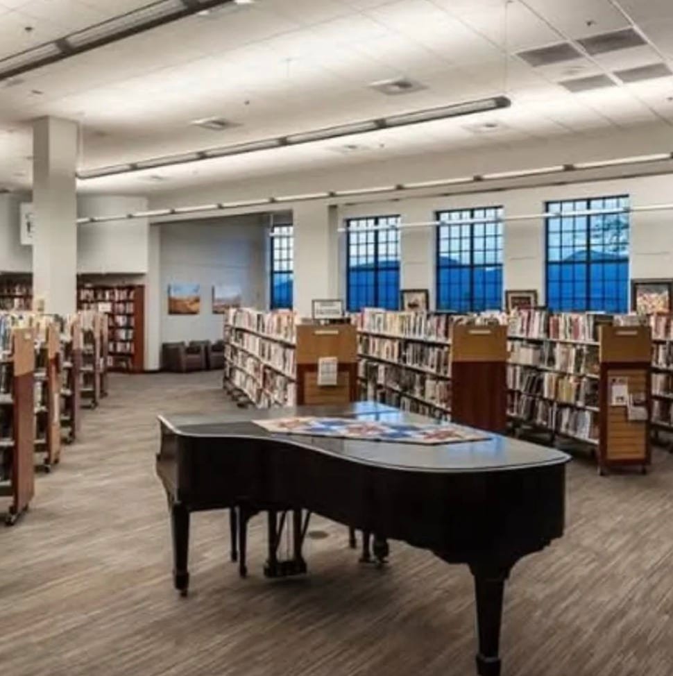 a photograph of a cultural center with a piano and book shelves