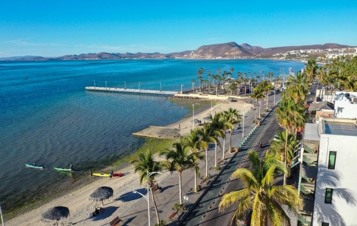 A photograph of La Paz, a beach town with palms, surfers, ocean and mountains
