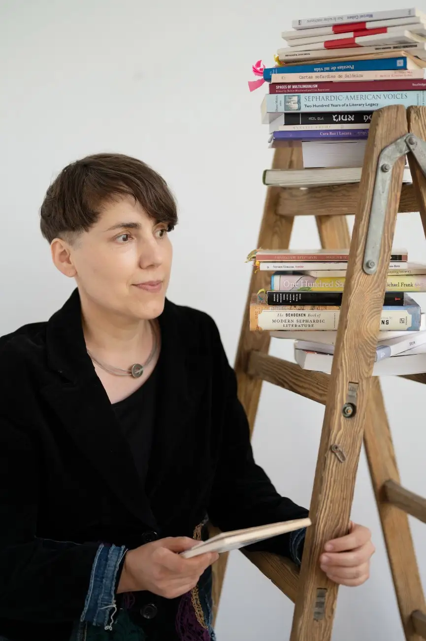 Agniezka-Ladino An image portraying Agniezka, our Ladino teacher right next to a wooden stair with some old books.