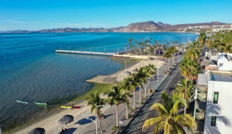 A photograph of La Paz, a beach town with palms, surfers, ocean and mountains
