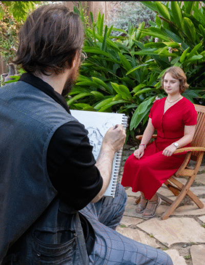 Oleg Tsank drawing a seated woman outdoors during a Yiddish portrait session at Yiddishland California.