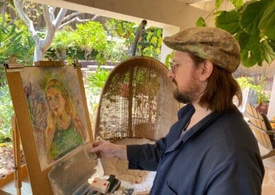 Oleg Tsank painting a colorful Yiddish portrait of a woman on an easel at Yiddishland California.