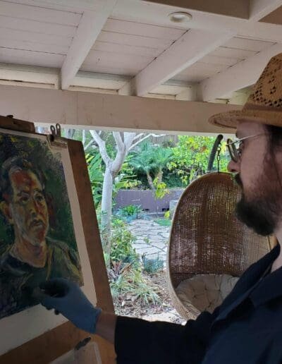 Oleg Tsank painting a Yiddish portrait of a man on an easel inside the studio at Yiddishland California.