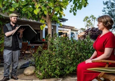 Oleg Tsank sketching a woman in a red dress during a Yiddish portrait session outdoors.